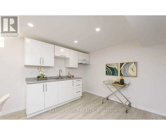 A kitchen with white cabinets and a painting on the wall.