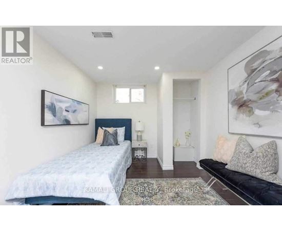 A bedroom with a bed, a couch, and a painting on the wall.