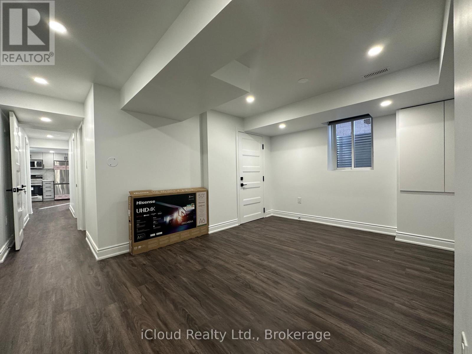 A spacious room with wooden flooring and a large window.