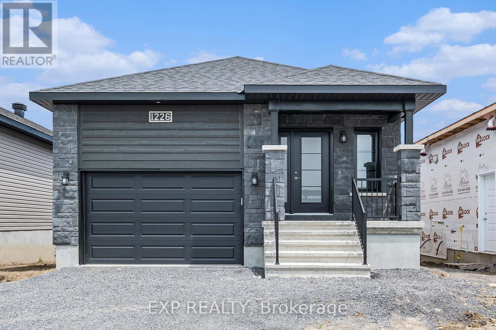 A grey house with a black garage door is for sale.