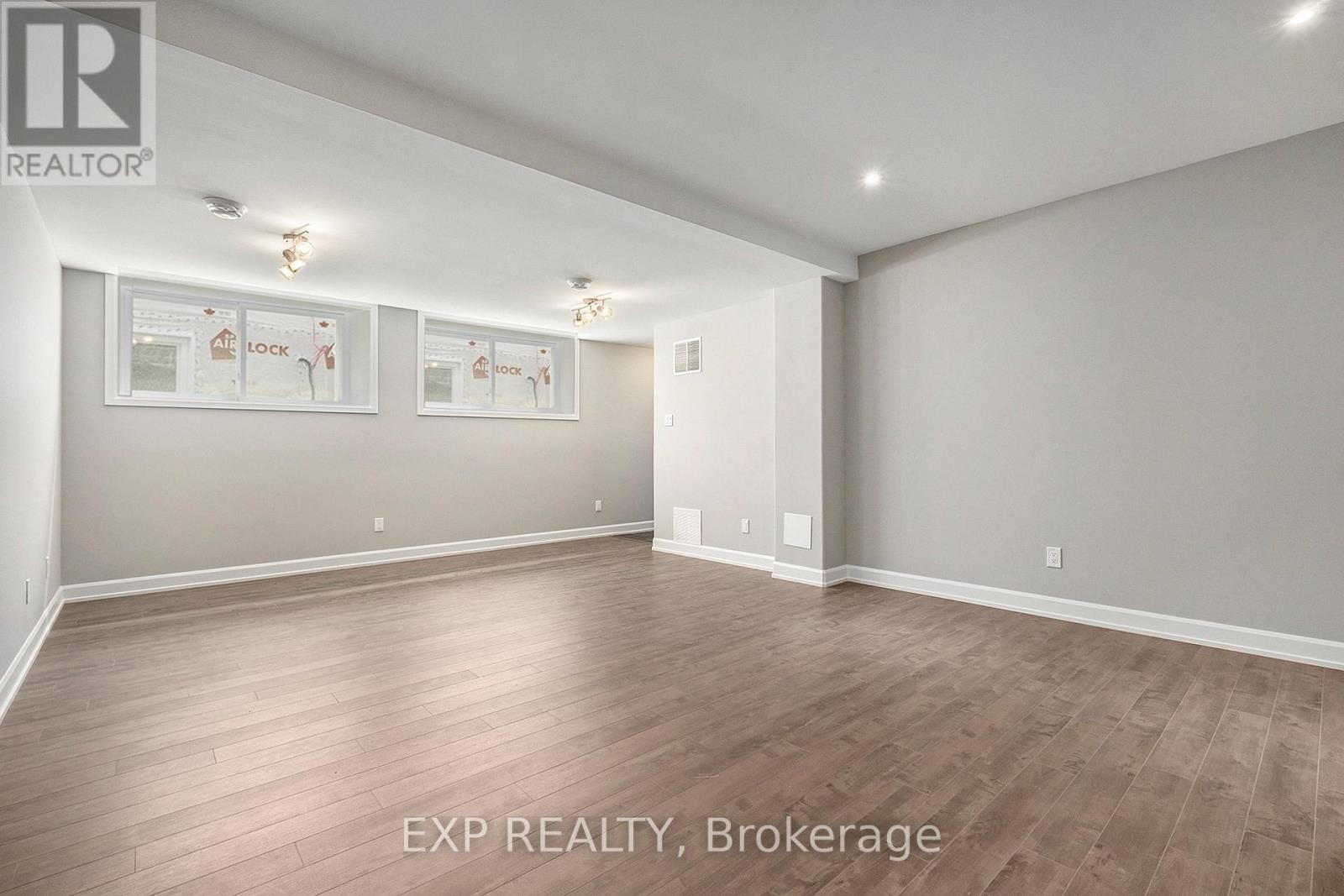 A large, empty room with wood flooring and white walls.