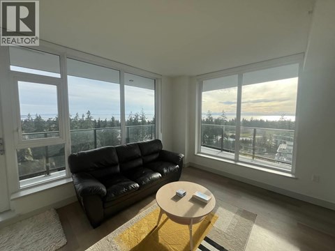A living room with a black couch and a coffee table in front of a window.