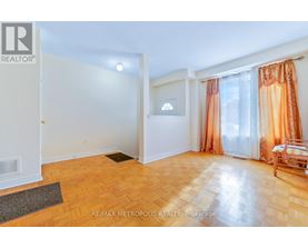 A room with a wooden floor and a window with orange curtains.