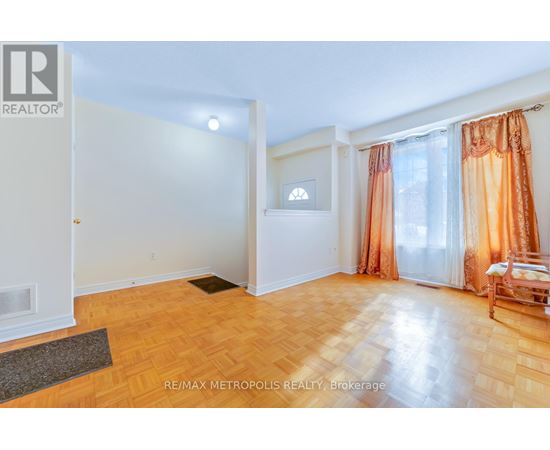 A room with a wooden floor and a window with orange curtains.
