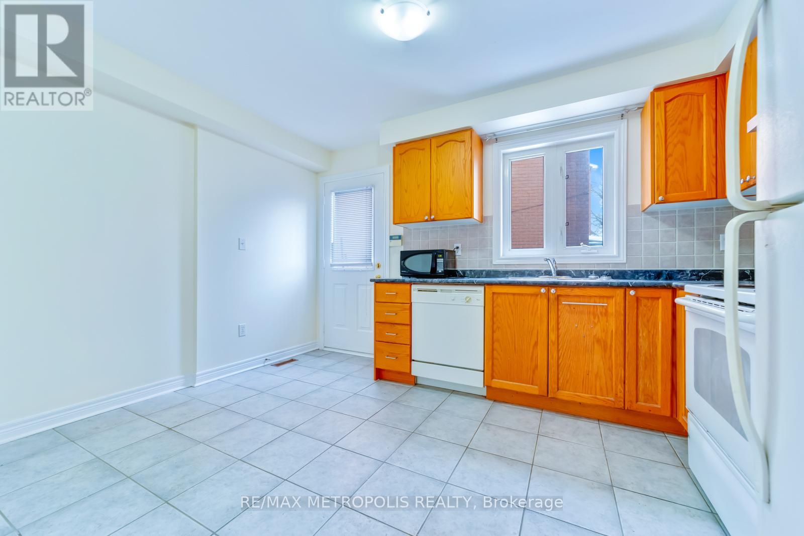 A kitchen with orange cabinets and white appliances.