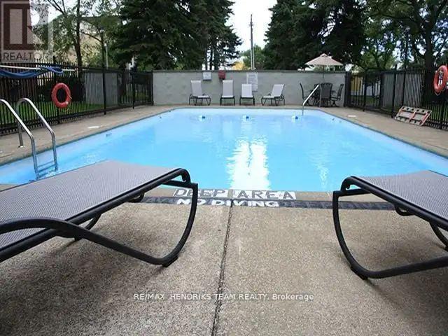 A pool surrounded by chairs and a fence.