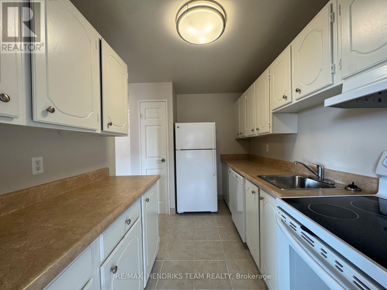 A kitchen with white cabinets and a white refrigerator.