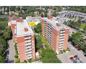 Two red brick apartment buildings with parking lots in front.