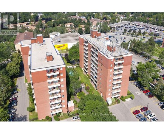 Two red brick apartment buildings with parking lots in front.