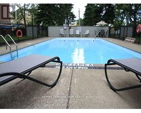 A pool surrounded by chairs and a fence.