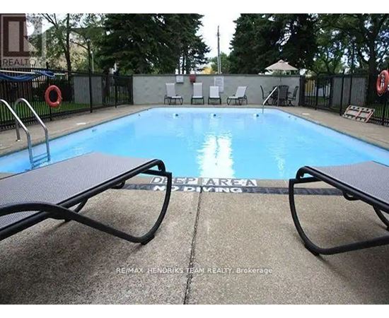 A pool surrounded by chairs and a fence.
