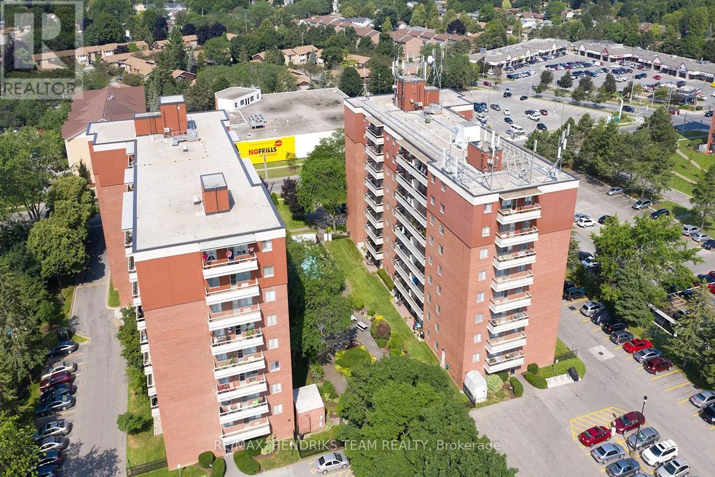 Two red brick apartment buildings with parking lots in front.