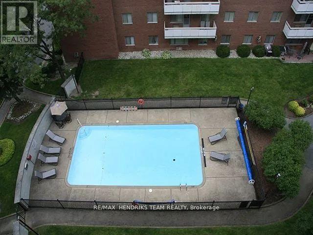 A swimming pool surrounded by a concrete deck and lounge chairs.