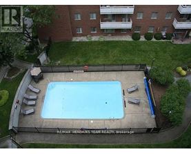 A swimming pool surrounded by a concrete deck and lounge chairs.