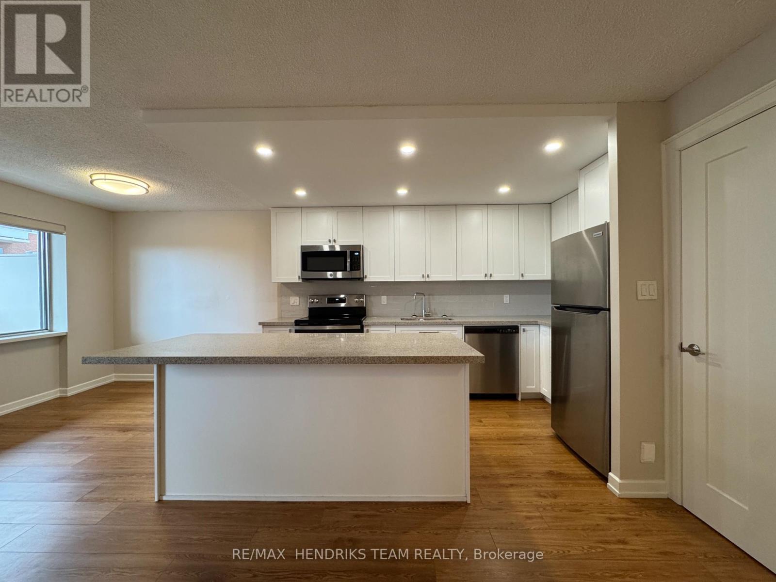 A kitchen with white cabinets and a wooden floor.