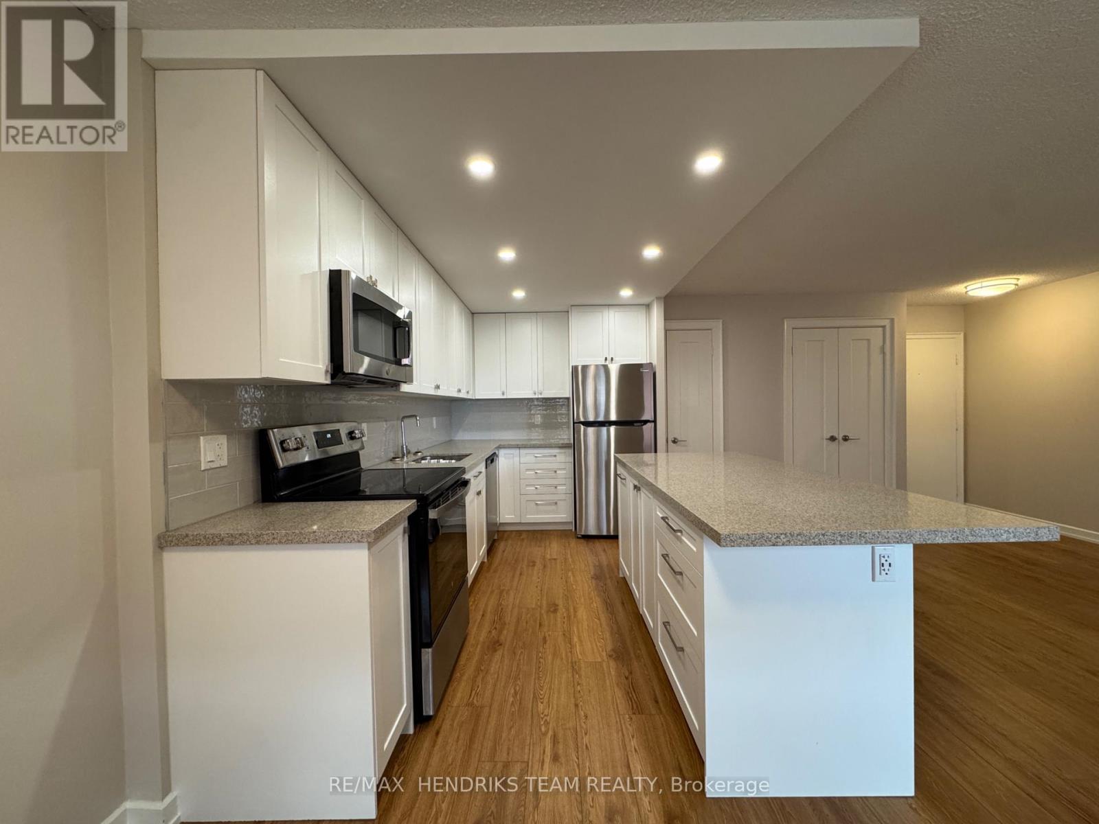 A kitchen with white cabinets and a wooden floor.