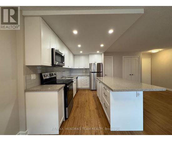 A kitchen with white cabinets and a wooden floor.