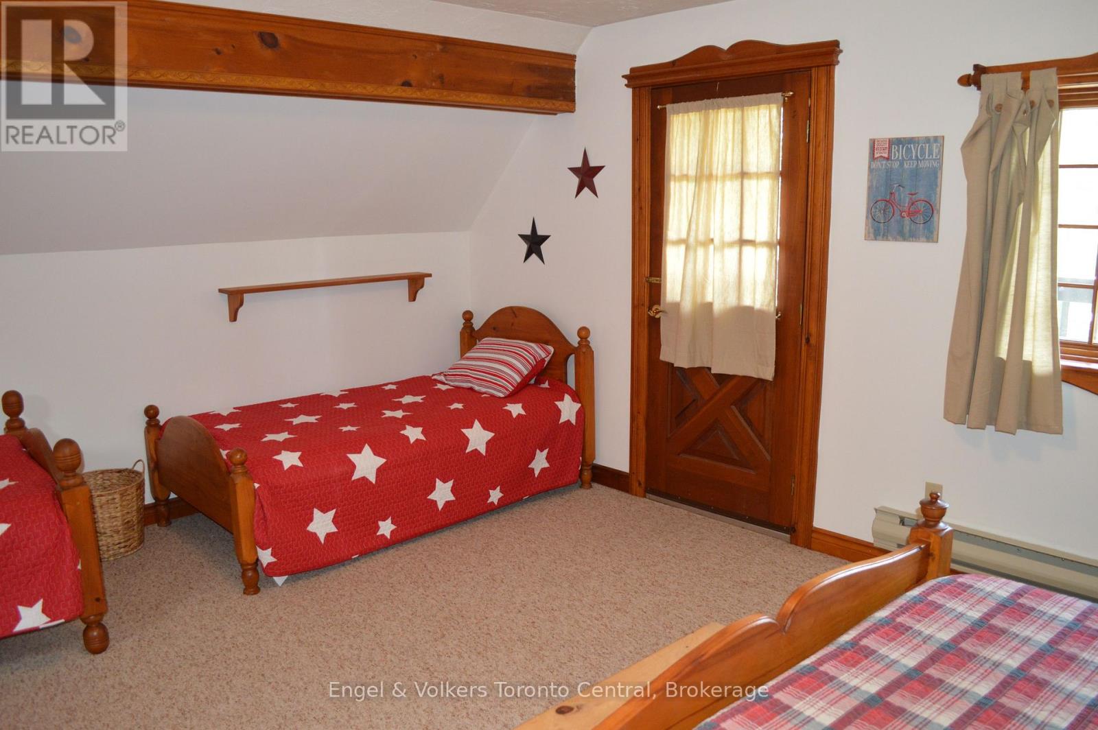 A bedroom with a bed covered in a red and white star print bedspread.