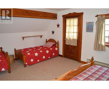 A bedroom with a bed covered in a red and white star print bedspread.