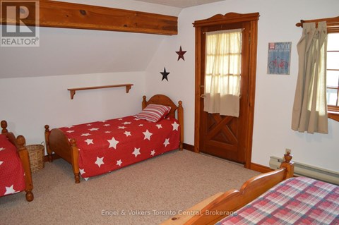 A bedroom with a bed covered in a red and white star print bedspread.