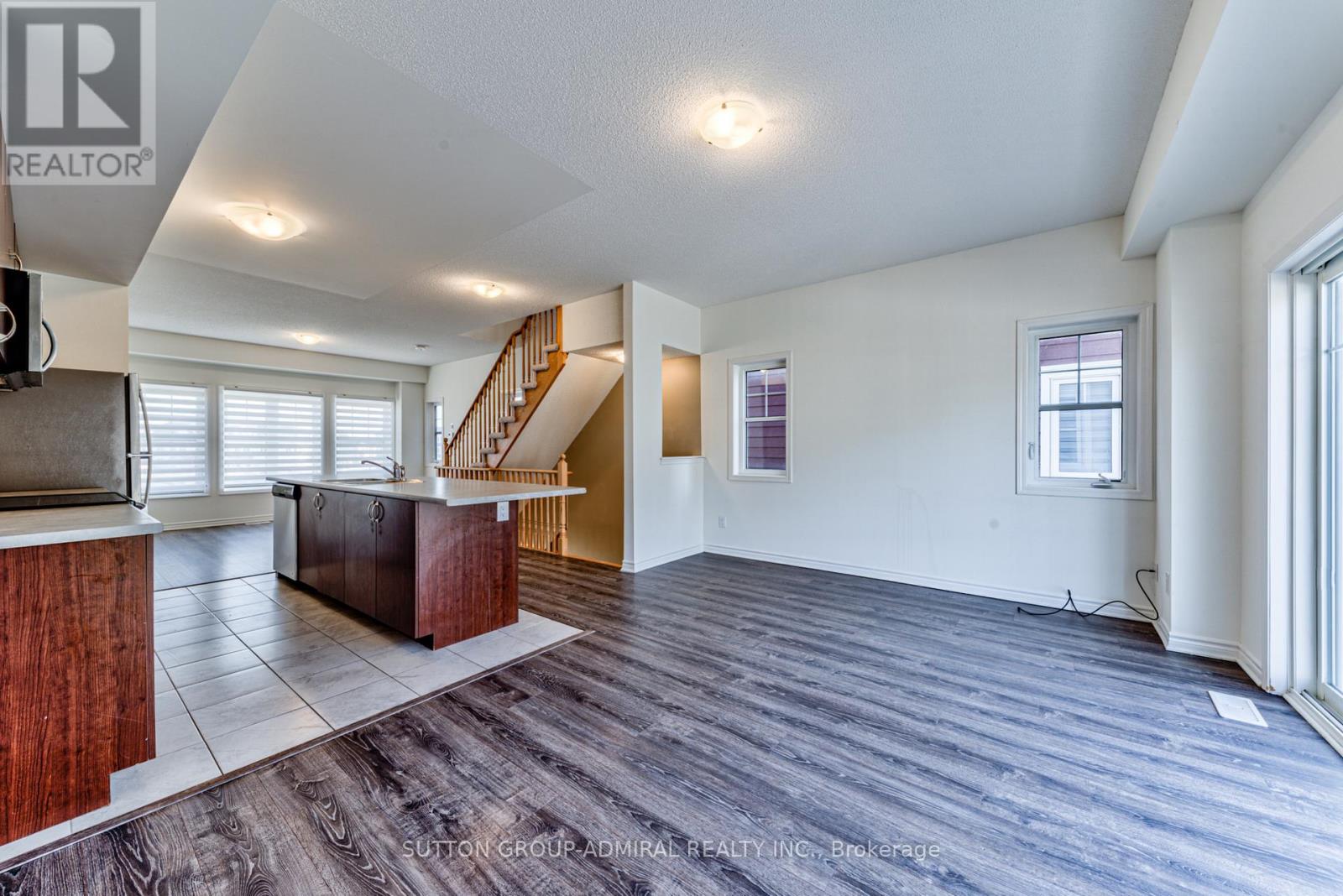 A spacious living room with a staircase leading to the upper floor.