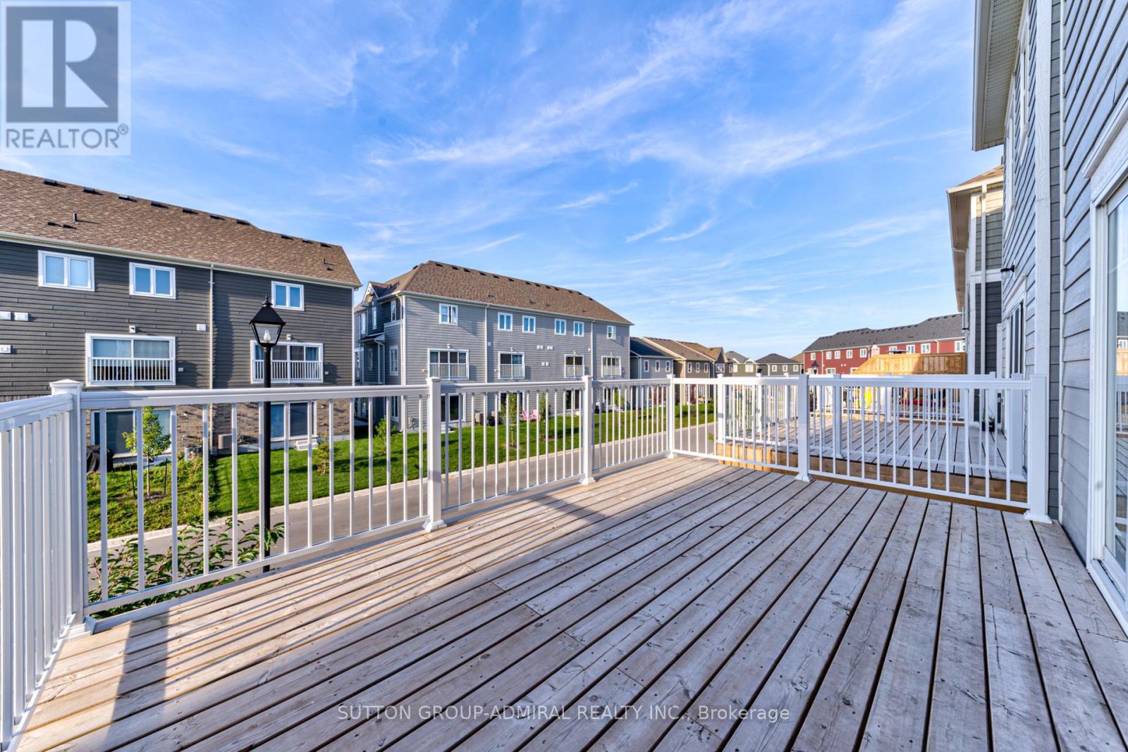 A wooden deck with a white railing in front of a building.