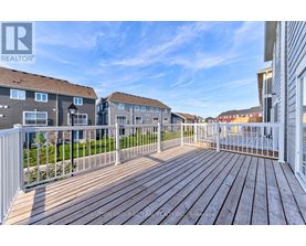 A wooden deck with a white railing in front of a building.