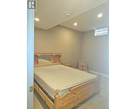 A bedroom with a bed, nightstand, and a window.