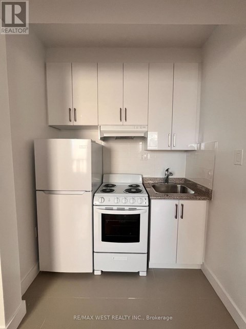 A white kitchen with a refrigerator, stove, and sink.