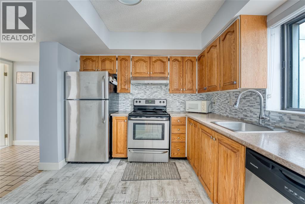 A kitchen with wooden cabinets and a stainless steel refrigerator.