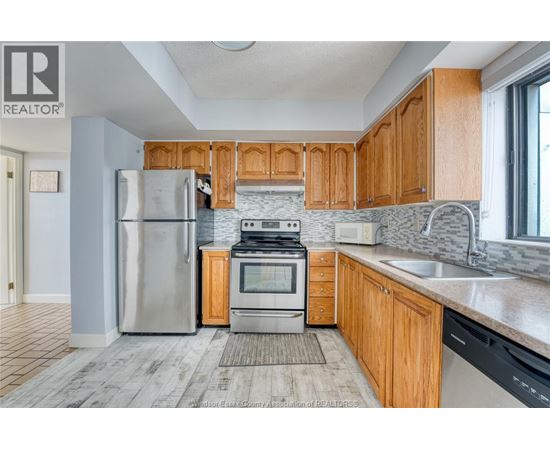 A kitchen with wooden cabinets and a stainless steel refrigerator.