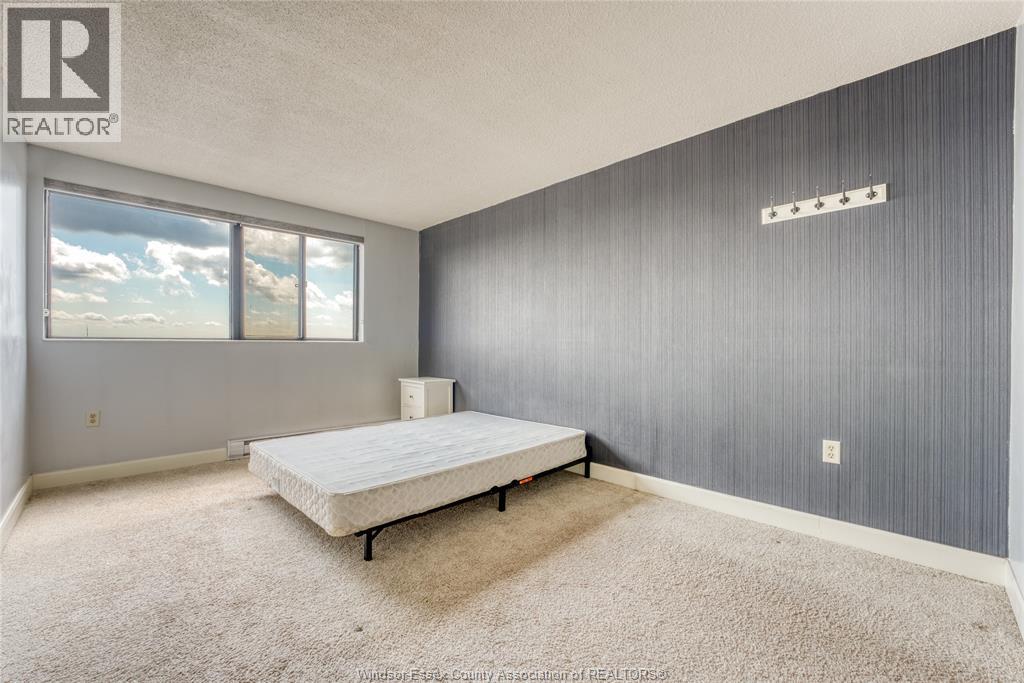 A bedroom with a bed, carpet, and a window.