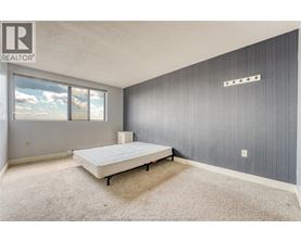A bedroom with a bed, carpet, and a window.