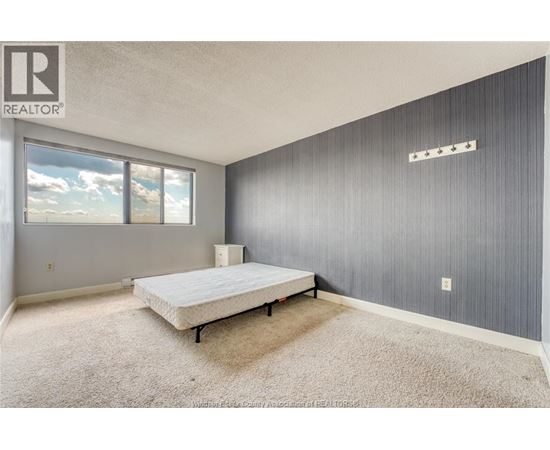 A bedroom with a bed, carpet, and a window.