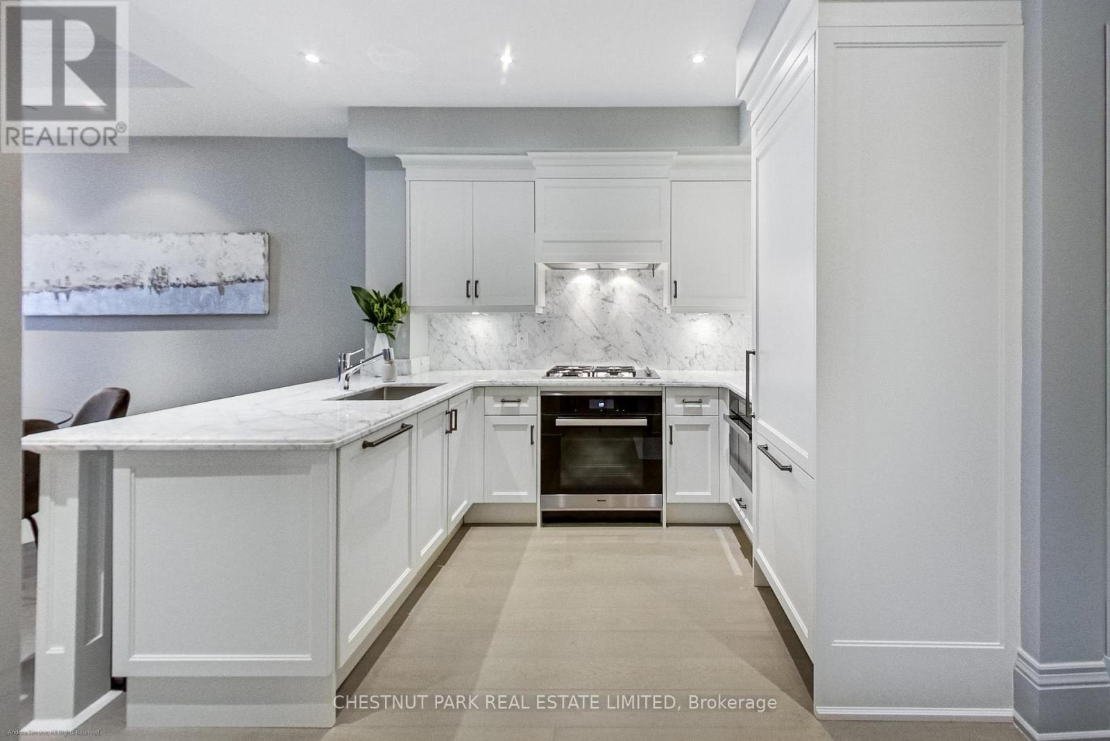 A modern kitchen with white cabinets and a marble countertop.