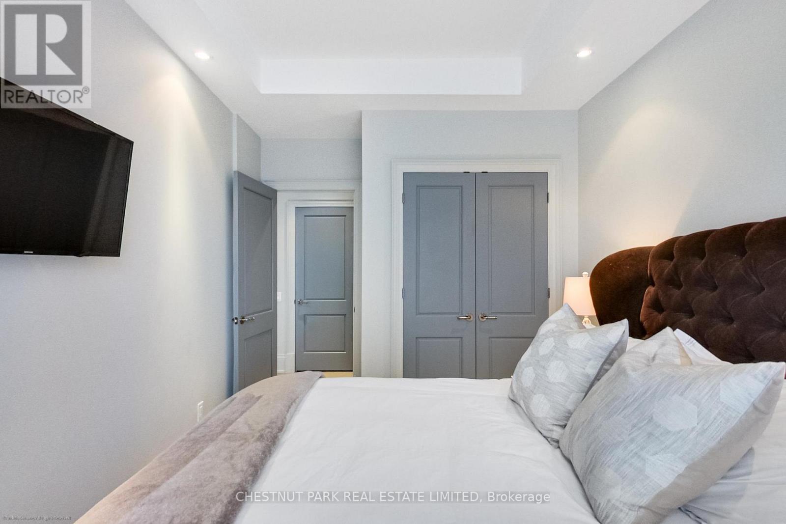 A bedroom with a large bed and a flat screen TV mounted on the wall.