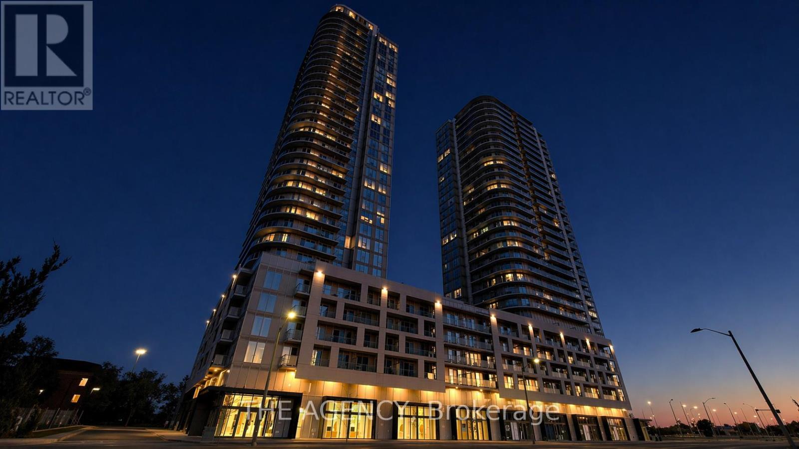 Two tall buildings with lit windows at night.