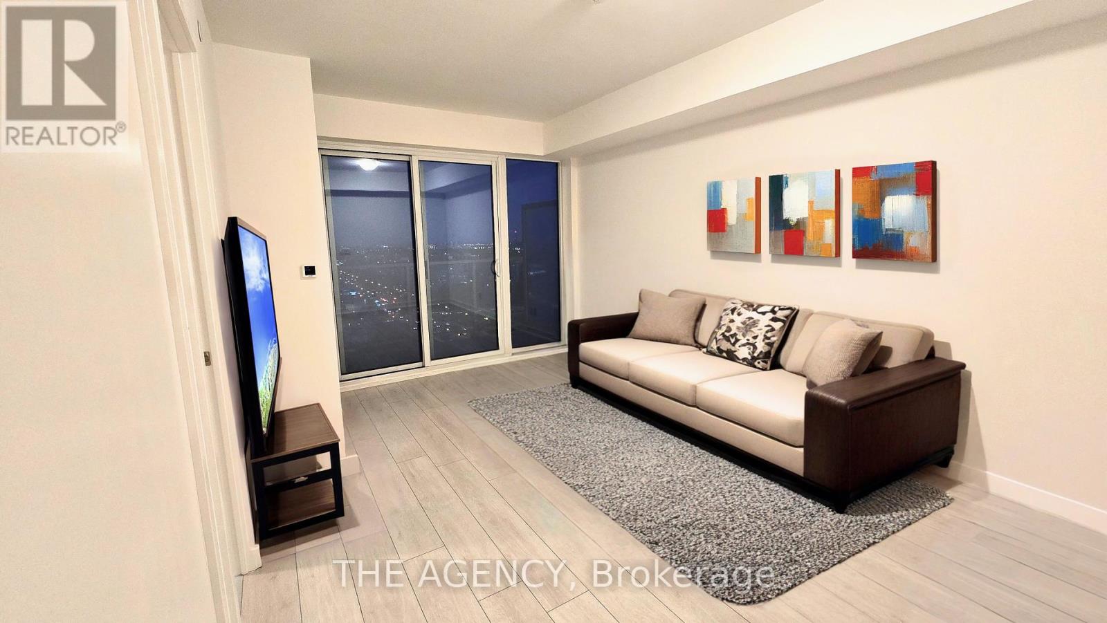 A living room with a couch, television, and a rug.