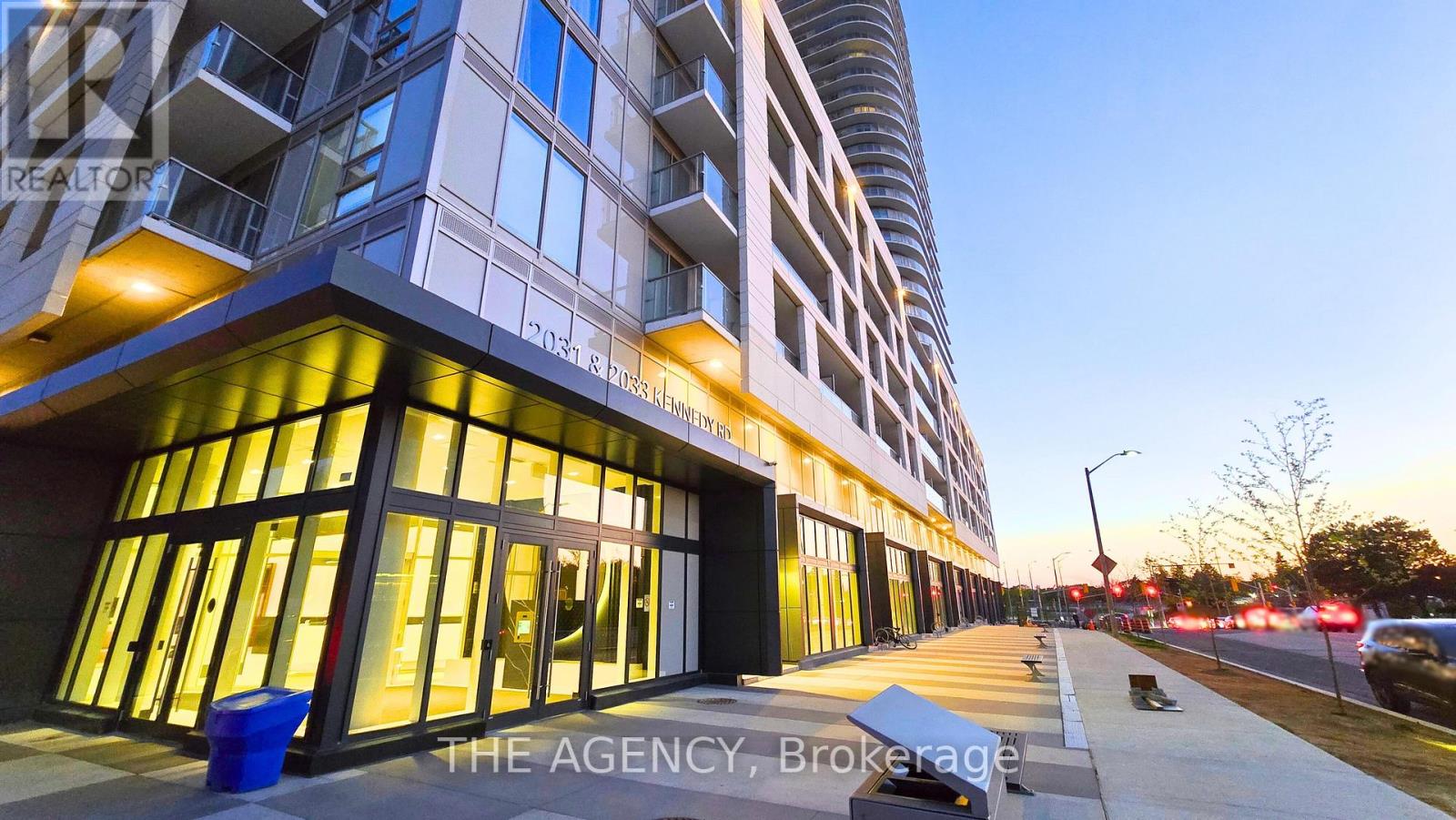 A modern building with a glass facade and a sign that reads "The Agency Brokerage."