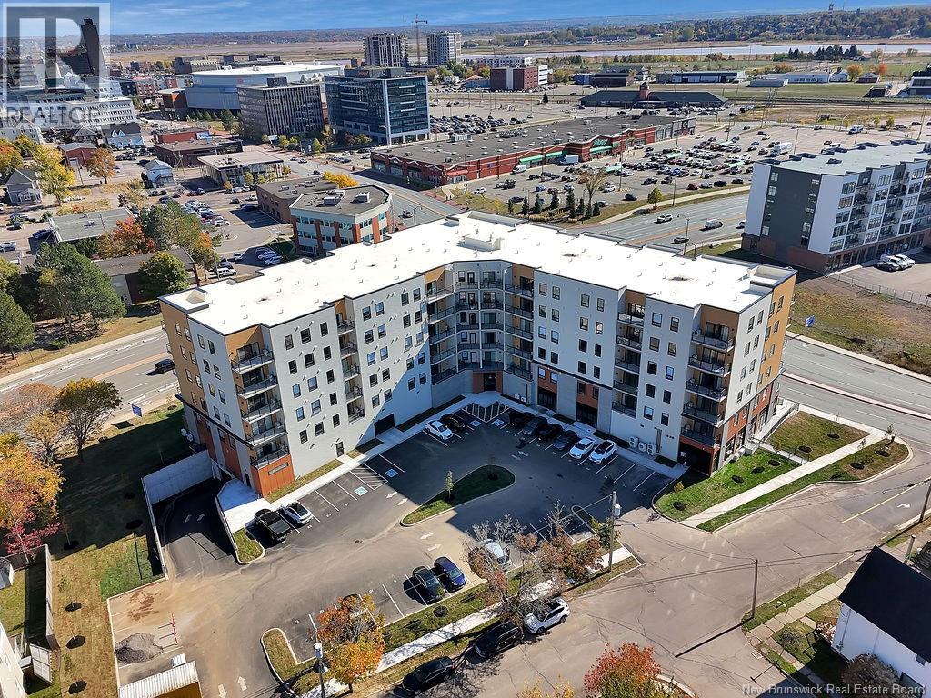 A large white apartment building with a parking lot in front.