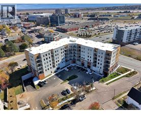A large white apartment building with a parking lot in front.