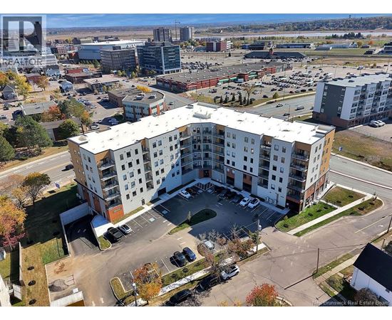 A large white apartment building with a parking lot in front.