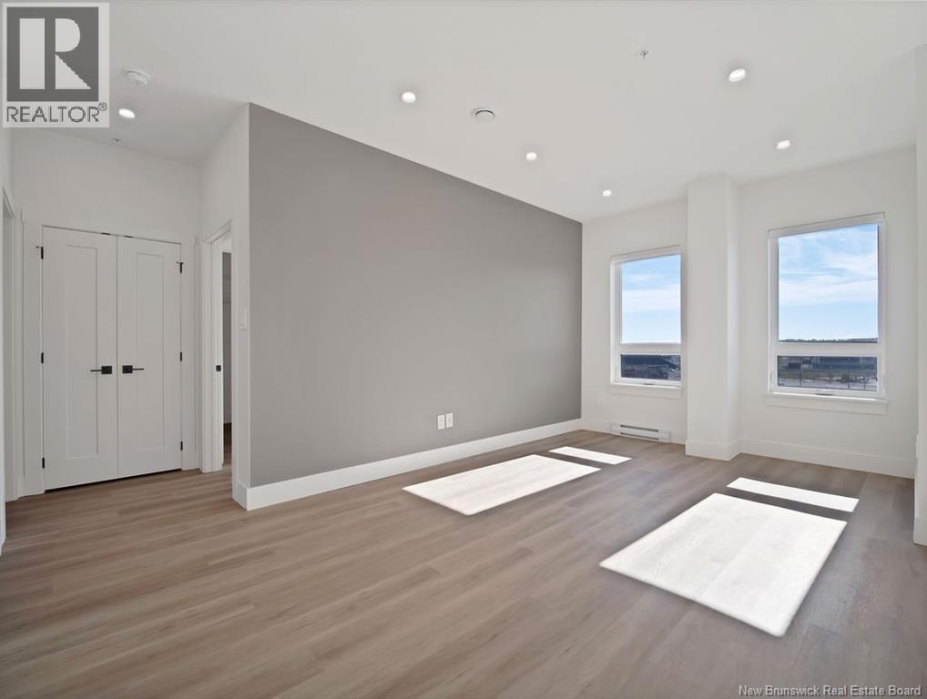 A spacious room with wooden floors and two windows.