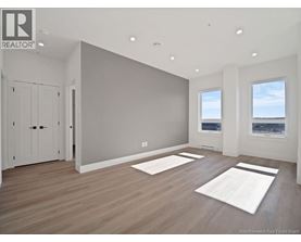 A spacious room with wooden floors and two windows.
