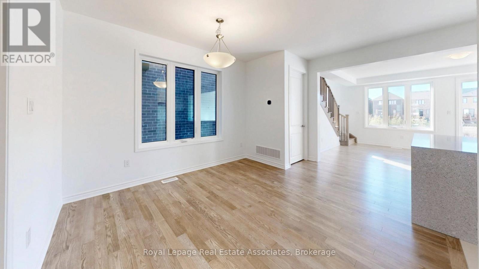 A spacious room with wooden flooring and a large window.