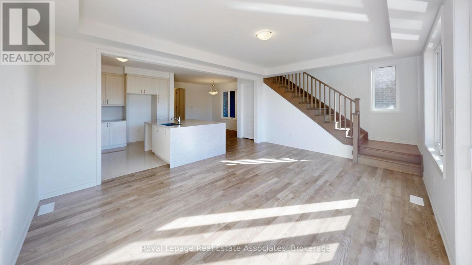 A spacious living room with a staircase leading to the upper floor.