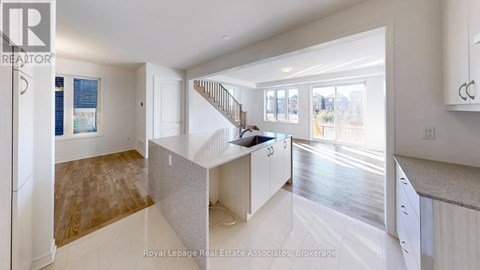 A spacious kitchen with white cabinets and a staircase leading to the upper level.