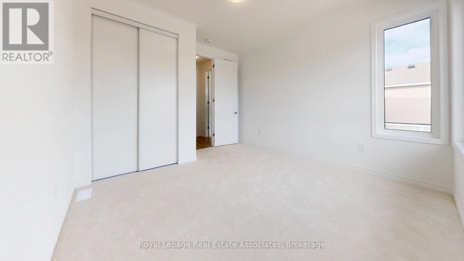 A white bedroom with a window and a door.