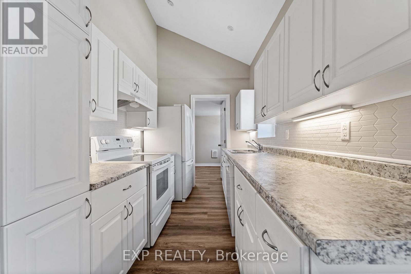 A kitchen with white cabinets and marble countertops.