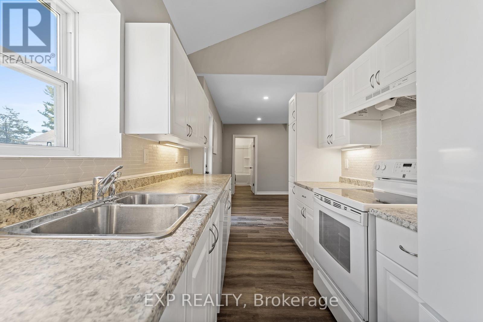 A kitchen with white cabinets and appliances is for sale.